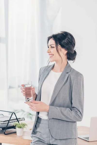 Hermosa Mujer Negocios Sonriente Traje Sosteniendo Vaso Agua Oficina —  Fotos de Stock