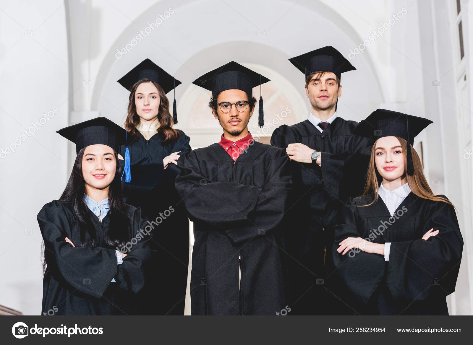 Cheerful Students Graduation Gowns Standing Crossed Arms