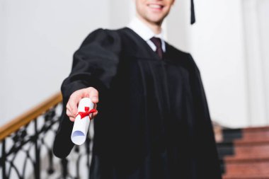 selective focus of diploma in hand of happy student in university  clipart