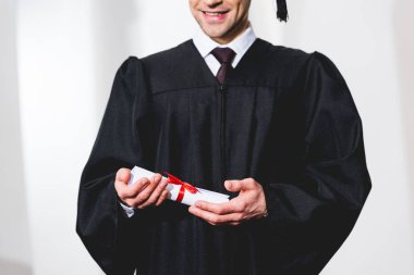 cropped view of happy young man smiling while holding diploma  clipart