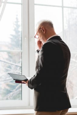 pencere yakınında dururken gözlük okuma kitabı olgun öğretmen 