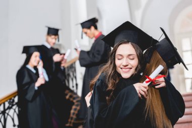 diploma tutan ve öğrencilerin yanında sarılma neşeli kız seçici odak 