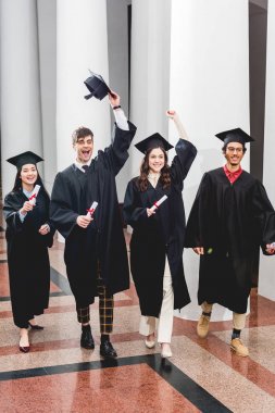 diplomalarını tutarken mezuniyeti kutlayan öğrenciler üzerine neşeli bir grup 