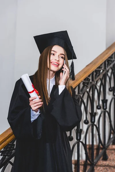 Cheerful Young Woman Holding Diploma While Talking Smartphone — Stock Photo, Image