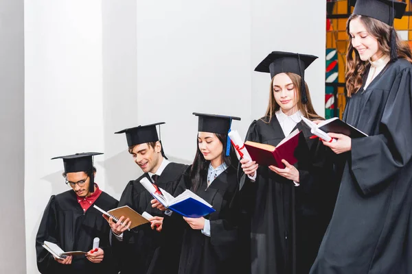 Vrolijke Studenten Afstudeer Jurken Die Diploma Houden Boeken Lezen — Stockfoto