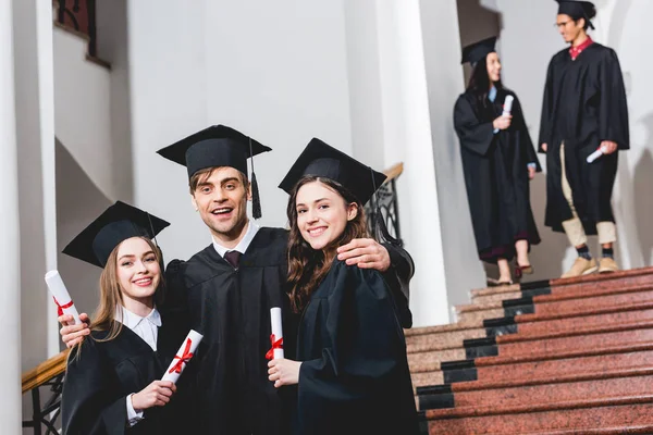 Selective Focus Cheerful Man Graduation Cap Hugging Attractive Girls While — Stock Photo, Image