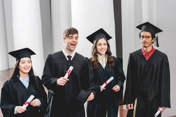 Diploma Tutan Mezuniyet Önlüklerinde Öğrenciler Üzerinde Gülümseyen Grup — Stok fotoğraf
