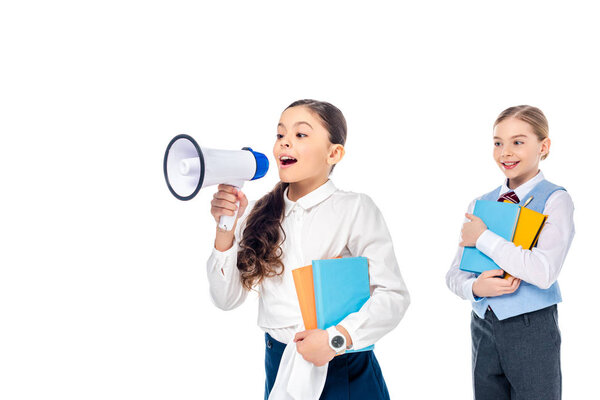 школьницы в формальной одежде, держащие книги и кричащие в мундштуке Изолированные на белом
