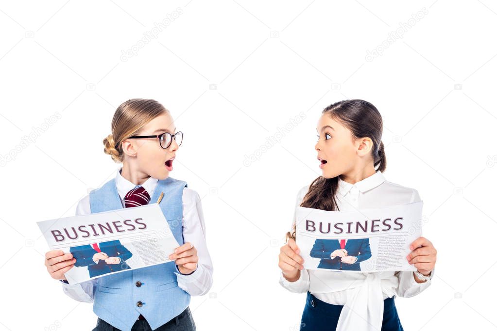 surprised schoolgirls in formal wear with business newspapers looking at each other Isolated On White