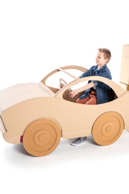 adorable boy playing with cardboard car on white with copy space clipart