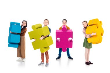 mutlu çocuklar kameraya bakıyor ve beyaz üzerinde yapboz parçaları tutarak 