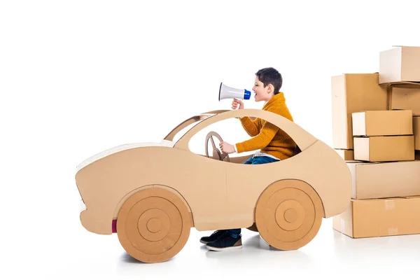 boy shouting in mouthpiece while playing with cardboard car on white