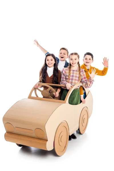 happy kids sitting in cardboard car, waving and cheering on white