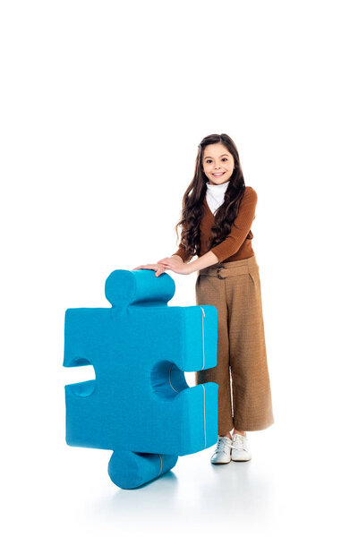 smiling kid with jigsaw puzzle piece looking at camera on white