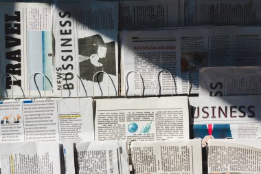 different print business and travel newspapers on stand in sunshine clipart