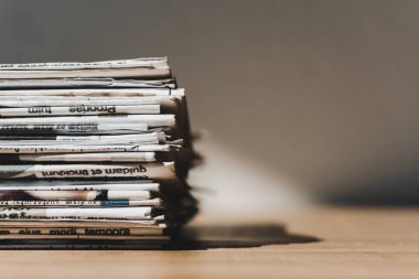 different print newspapers in pile on wooden table with shadow clipart