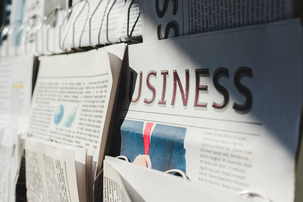 selective focus of different print newspapers on stand in sunlight