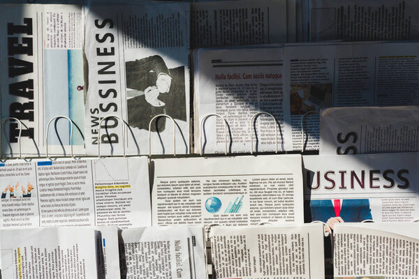 different print business and travel newspapers on stand in sunshine