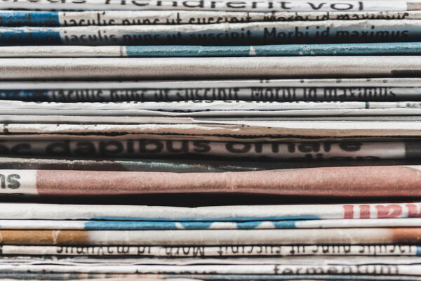 close up of different print daily newspapers in pile 