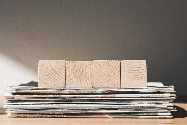 empty wooden blocks with copy space on pile of print newspapers