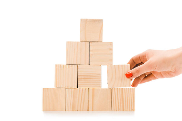 обрезанный вид женщины поднимая один деревянный блок с копией пространства от пирамиды изолированы на белом
