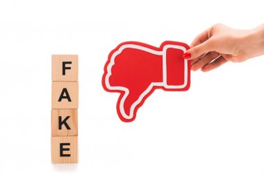 beyaz izole sahte kelime ile ahşap bloklar yakınında kırmızı başparmak aşağı işareti tutan kadın kırpılmış görünümü