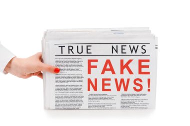 partial view of woman holding pile of newspapers with fake and true news isolated on white clipart