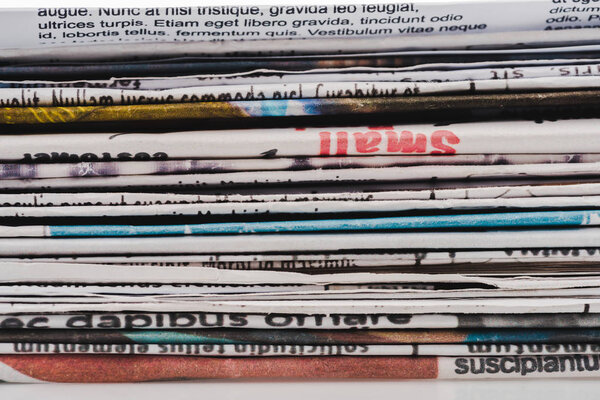 background with different print daily newspapers in pile 