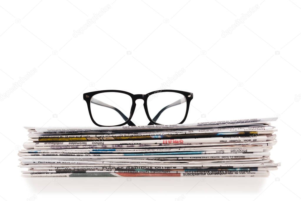 stack of daily newspapers with glasses on top isolated on white
