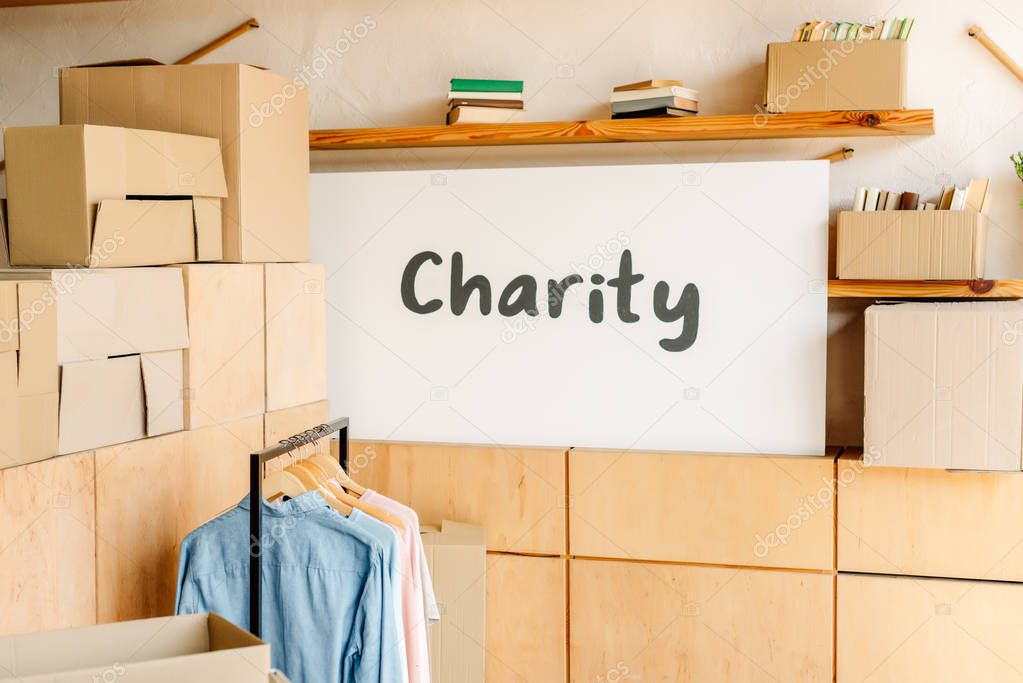 wooden cabinets, carton boxes, rack with shirts and placard with charity inscription