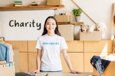 gönüllü yazıt gülümseyen ve kameraya bakarak beyaz t-shirt gülümseyen asyalı kız