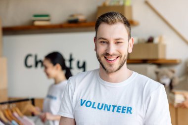 selective focus of handsome young man in white t-shirt with volunteer inscription clipart