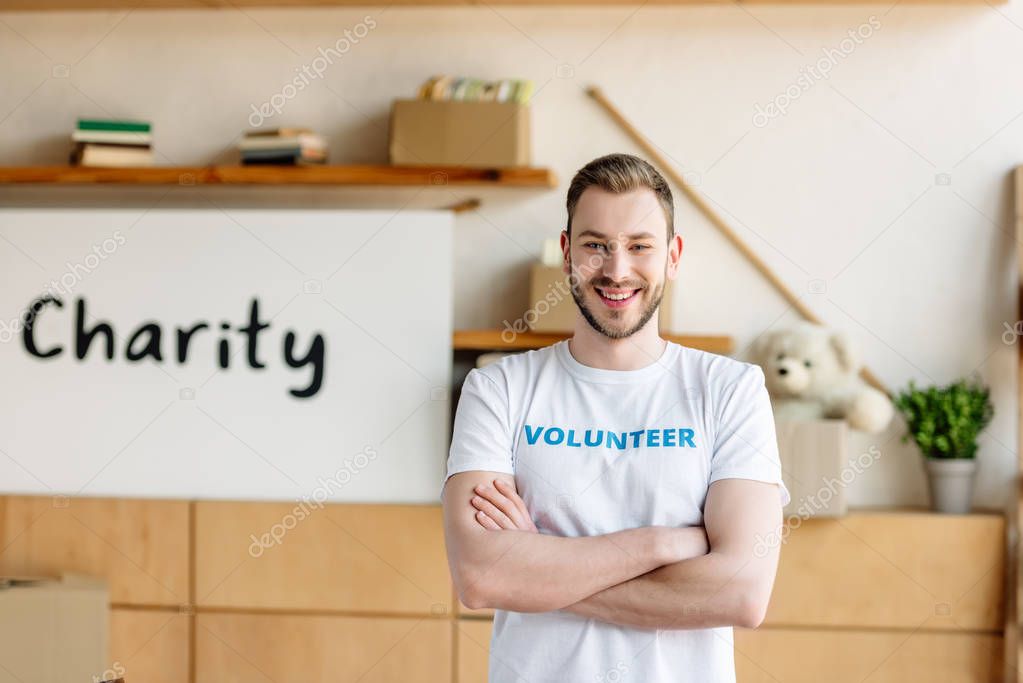 good-looking young volunteer with crossed arms smiling and looking at camera