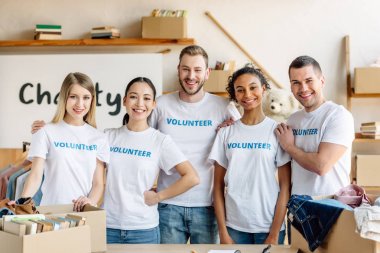 five young, multicultural volunteers standing together, smiling and looking at camera  clipart