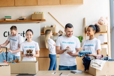 yardım merkezinde çalışan gönüllü yazıtlar ile beyaz t-shirt genç çok kültürlü gönüllü grubu