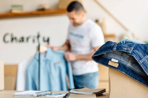 Selective Focus Young Volunteer Standing Rack Shirts Cardboard Box Jeans — Stock Photo, Image