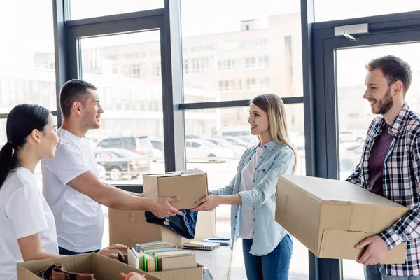 Young Multicultiral Volunteers Giving Cardboard Boxes Smiling Man Woman — Stock Photo, Image
