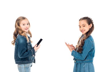 beyaz izole akıllı telefonlar kullanarak denim giysiler iki çocuk