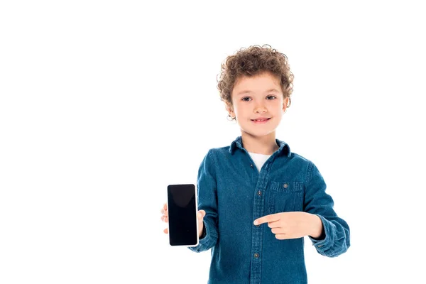 白で隔離された空白の画面でスマートフォンに指で指を向けているデニムシャツのカーリー子供の正面図 — ストック写真