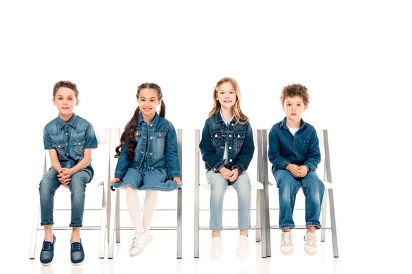 Czworo Dzieci Dżinsowych Ubraniach Siedzących Krzeseł Białym — Zdjęcie stockowe