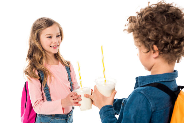 selective focus of two schoolkids holding milkshakes isolated on white