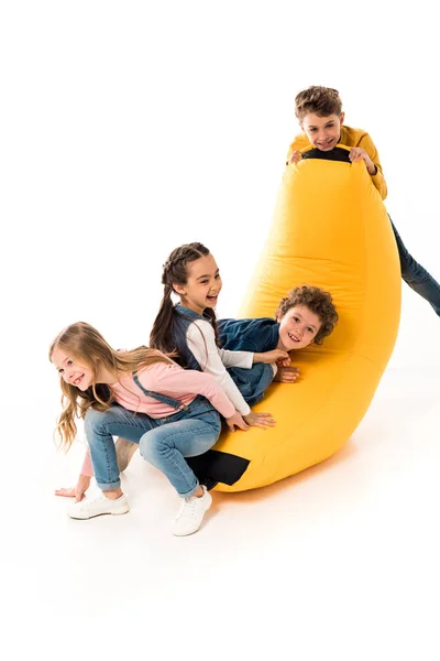 Vier Lächelnde Kinder Spielen Mit Sitzsack Stuhl Auf Weiß — Stockfoto