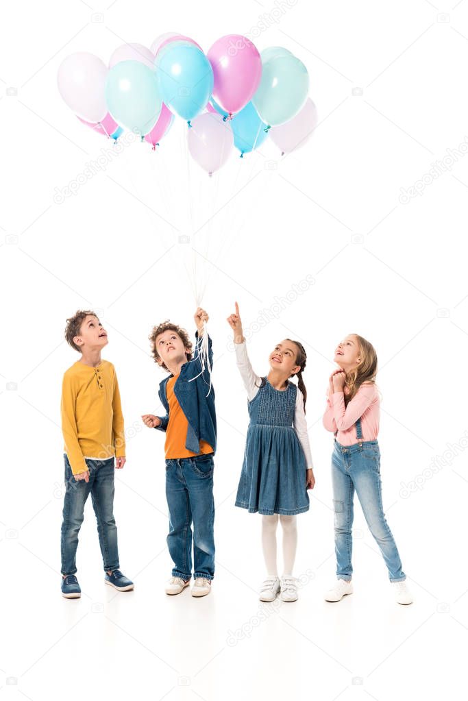 full length view of four kids holding balloons isolated on white