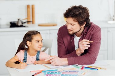 sevimli kızı kağıt parmak ile işaret yakışıklı baba bakıyor 