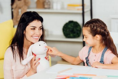 mutlu anne yakın yumuşak oyuncak parmak ile işaret sevimli kızı 