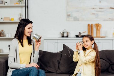 neşeli anne tutarak ve mutlu kızı ile oynarken konuşuyor  