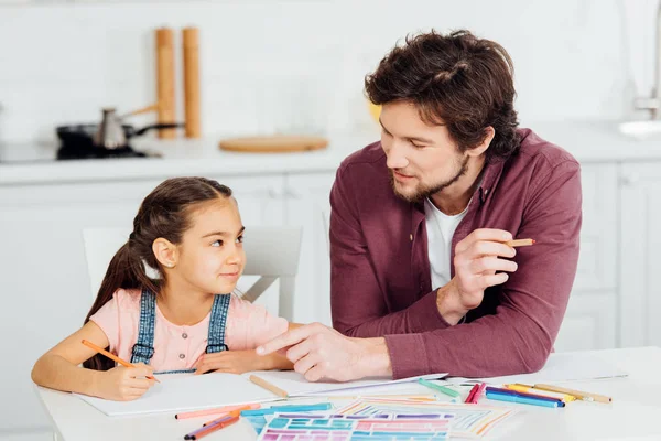 可爱的女儿看着英俊的父亲指着纸 — 图库照片