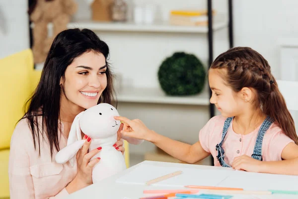 Carino Figlia Che Punta Con Dito Morbido Giocattolo Vicino Felice — Foto Stock