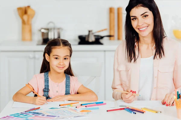 Neşeli Anne Sevimli Kızı Kameraya Bakarak Renkli Kalemler Tutarken Gülümseyerek — Stok fotoğraf