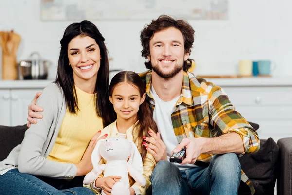 Niño Alegre Sosteniendo Juguete Suave Sentado Cerca Padres Felices Casa — Foto de Stock